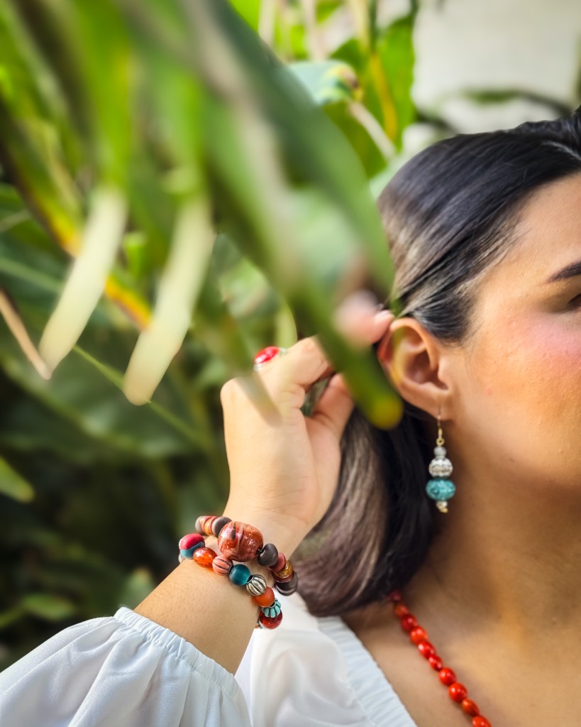 Retrato íntimo de una participante con joyería artesanal, tocándose el cabello